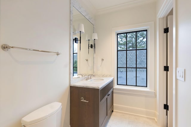 bathroom with toilet, vanity, baseboards, and ornamental molding