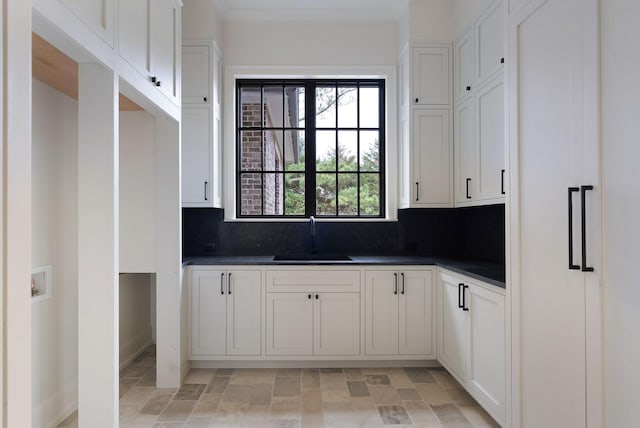 kitchen with dark countertops, white cabinetry, tasteful backsplash, and a sink