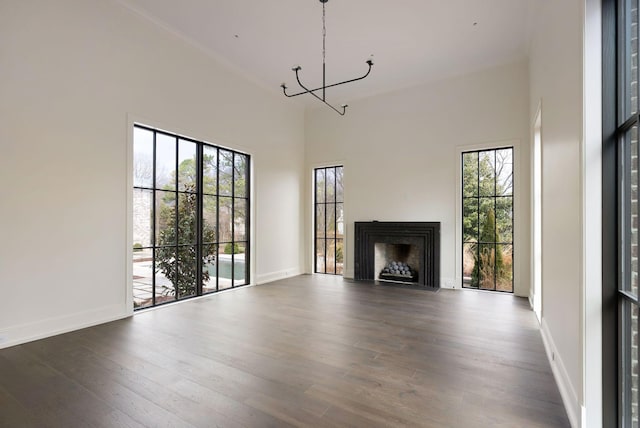 unfurnished living room with an inviting chandelier, dark wood-type flooring, a fireplace, and baseboards