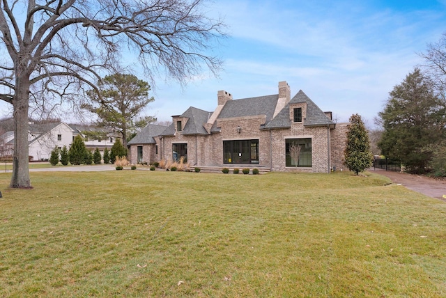 view of front of property featuring brick siding, a chimney, and a front yard