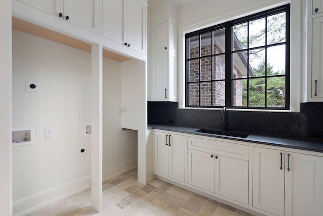 kitchen with dark countertops, decorative backsplash, baseboards, and a sink