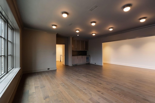 unfurnished living room featuring dark wood finished floors, visible vents, baseboards, and ornamental molding