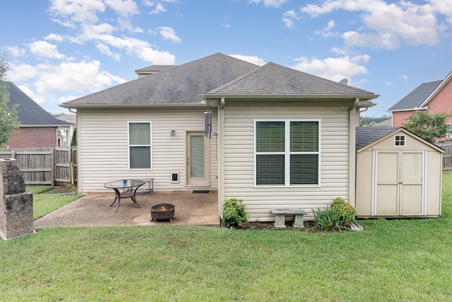 rear view of property with a lawn, a patio, a fire pit, and a storage unit