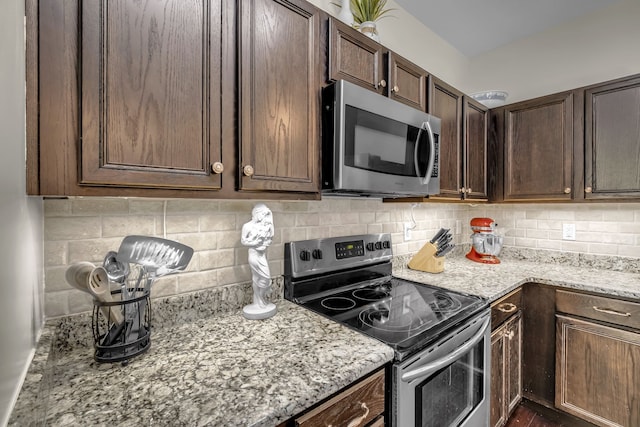 kitchen featuring light stone countertops, appliances with stainless steel finishes, dark brown cabinetry, and tasteful backsplash