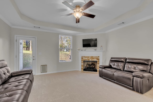 carpeted living room featuring ceiling fan, crown molding, a tile fireplace, and a tray ceiling