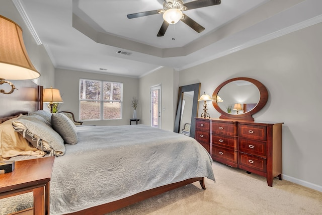 carpeted bedroom with a tray ceiling, ceiling fan, and crown molding