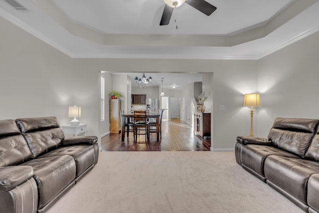 living room featuring ceiling fan with notable chandelier, dark hardwood / wood-style floors, a tray ceiling, and crown molding