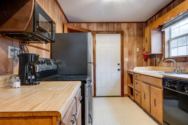 kitchen with crown molding, wooden walls, sink, and black appliances