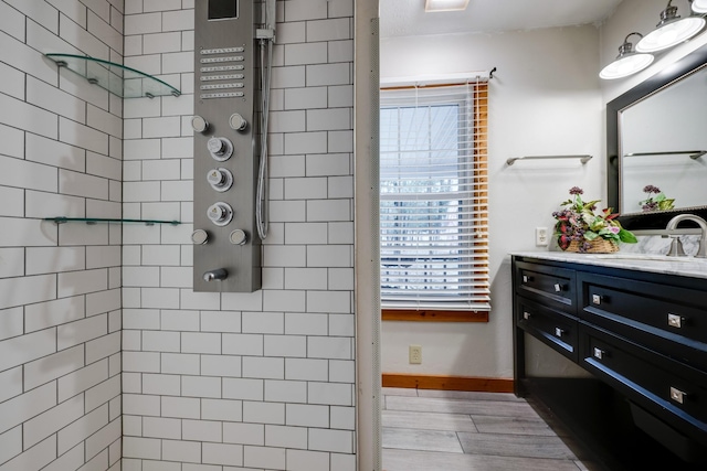 bathroom featuring hardwood / wood-style floors, vanity, and tiled shower