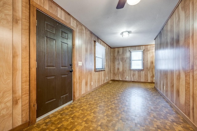 interior space featuring dark parquet floors, ceiling fan, and wooden walls