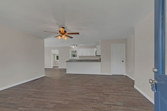 unfurnished living room featuring dark hardwood / wood-style flooring and ceiling fan