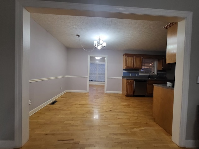 kitchen with stainless steel dishwasher, a notable chandelier, light wood-type flooring, and a textured ceiling