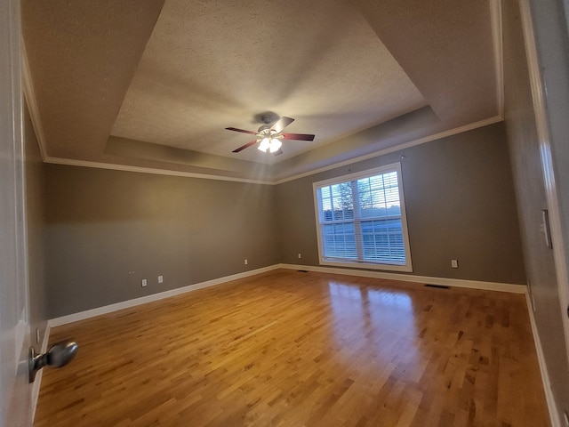 unfurnished room with ornamental molding, a textured ceiling, a raised ceiling, ceiling fan, and wood-type flooring