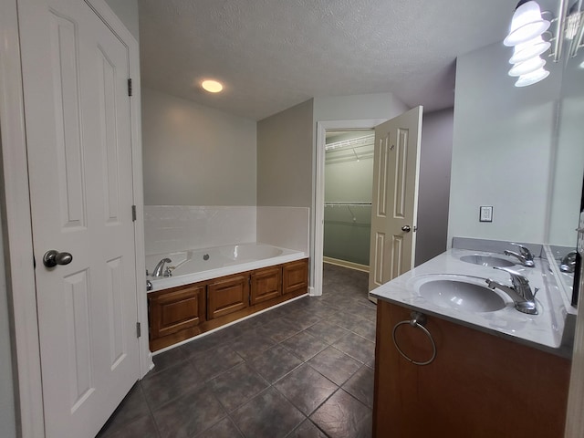 bathroom featuring a textured ceiling, tile patterned flooring, a tub to relax in, and vanity