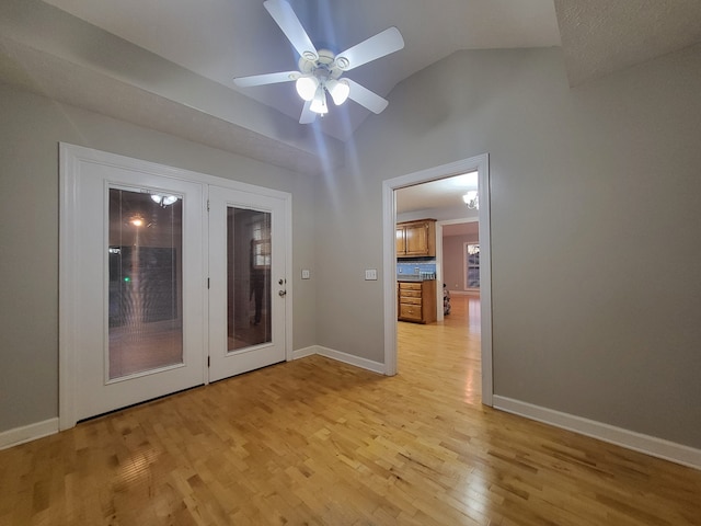 spare room featuring light wood-type flooring, vaulted ceiling, and ceiling fan