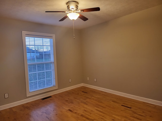 empty room with ceiling fan, a textured ceiling, and hardwood / wood-style flooring