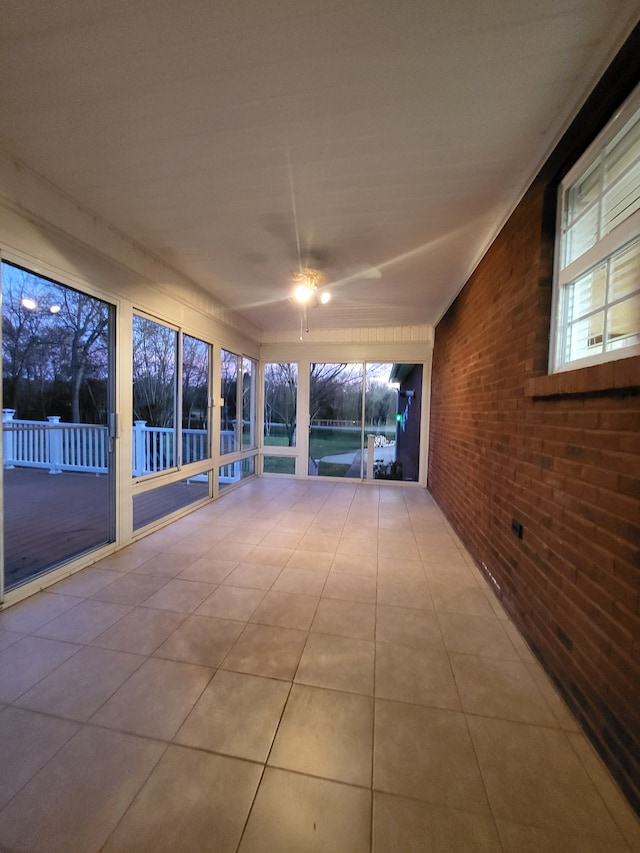 unfurnished sunroom featuring ceiling fan