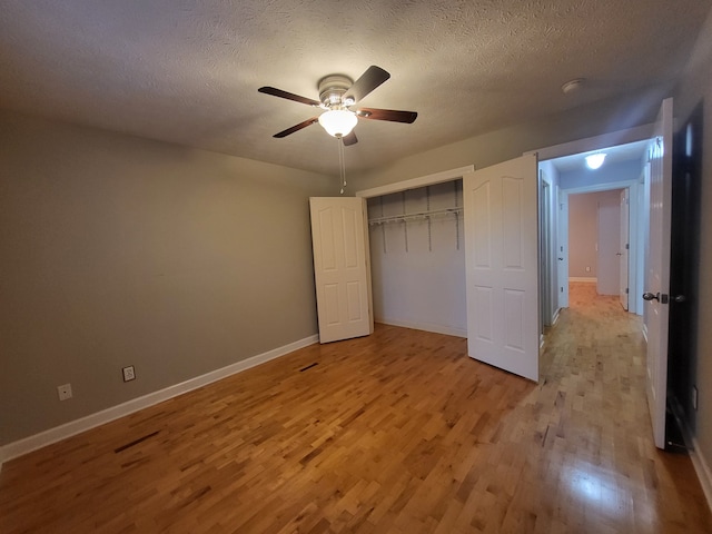 unfurnished bedroom featuring ceiling fan, light hardwood / wood-style floors, a textured ceiling, and a closet