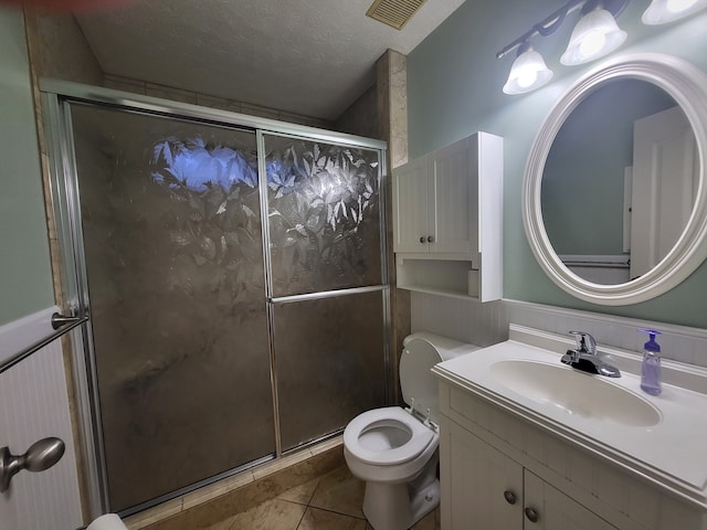 bathroom with vanity, a textured ceiling, toilet, and a shower with shower door