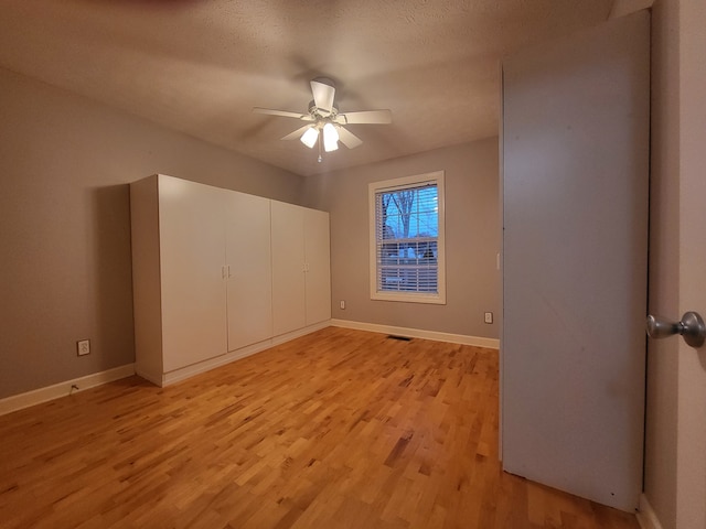 unfurnished bedroom with ceiling fan, a textured ceiling, and light wood-type flooring