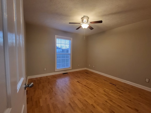 empty room featuring ceiling fan, wood-type flooring, and a textured ceiling