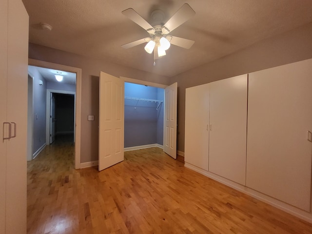 unfurnished bedroom with ceiling fan, a textured ceiling, and light wood-type flooring