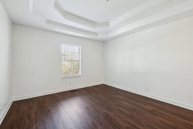 unfurnished room featuring dark hardwood / wood-style flooring, a tray ceiling, and crown molding