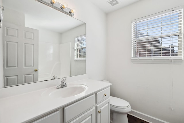 bathroom featuring walk in shower, vanity, toilet, and a wealth of natural light