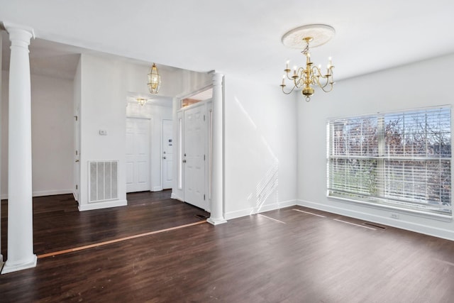 unfurnished room featuring ornate columns, dark hardwood / wood-style floors, and a notable chandelier