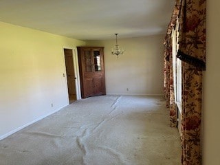 carpeted spare room featuring a notable chandelier