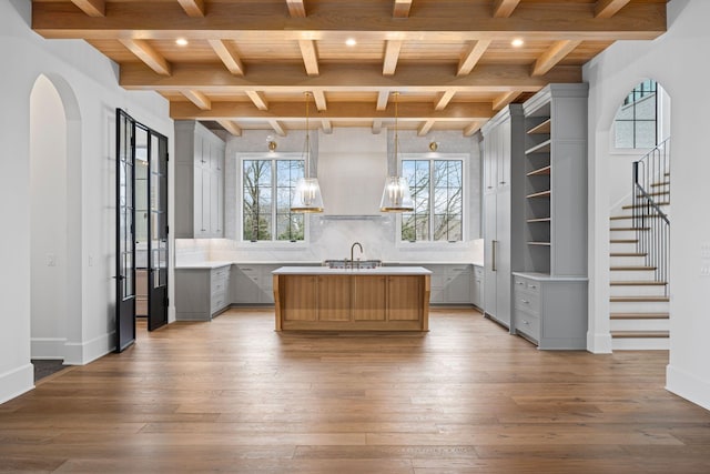 kitchen with a center island with sink, light countertops, hardwood / wood-style floors, and gray cabinetry