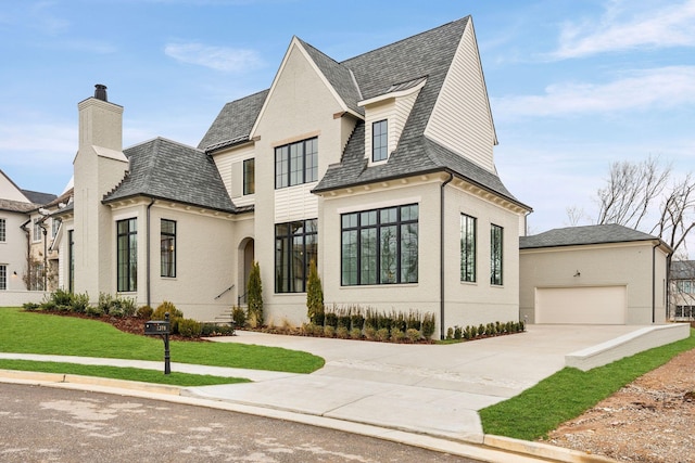 view of front facade featuring a garage, driveway, a chimney, and a front lawn