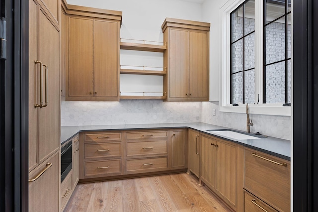 kitchen with dark countertops, a sink, light wood-style floors, open shelves, and a wealth of natural light