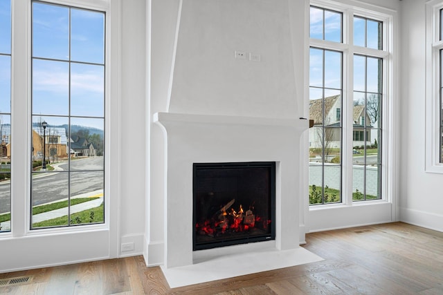 interior space with a fireplace with flush hearth, visible vents, plenty of natural light, and light wood finished floors