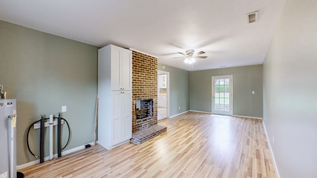 unfurnished living room featuring ceiling fan, light hardwood / wood-style flooring, gas water heater, and a brick fireplace