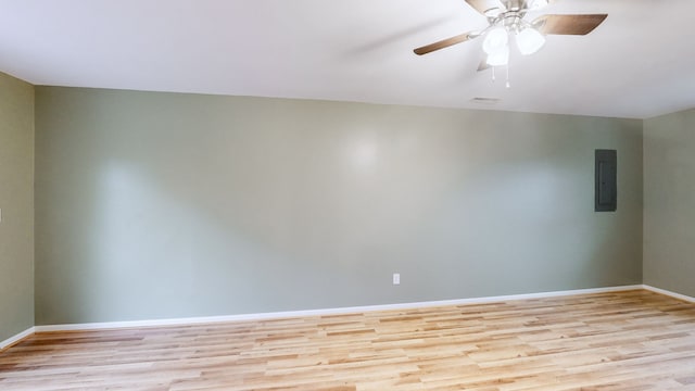 empty room with electric panel, ceiling fan, and light hardwood / wood-style floors