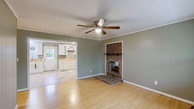 unfurnished living room with a brick fireplace, ceiling fan, ornamental molding, and light wood-type flooring