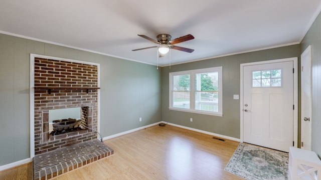 entrance foyer with ceiling fan, a fireplace, light hardwood / wood-style floors, and ornamental molding