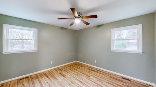 empty room featuring a wealth of natural light, ceiling fan, and light wood-type flooring