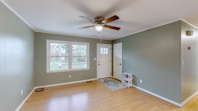 foyer featuring ceiling fan, light wood-type flooring, ornamental molding, and wooden walls