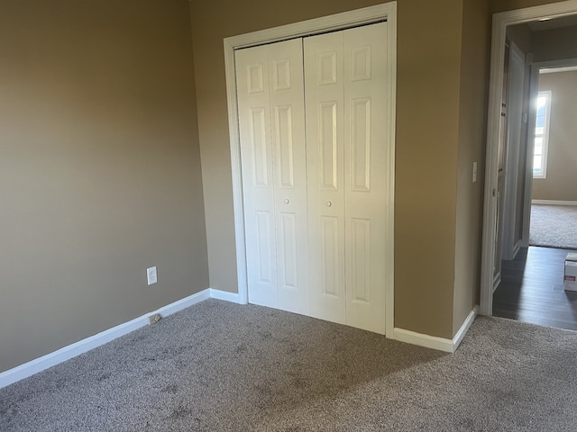 unfurnished bedroom with dark carpet and a closet