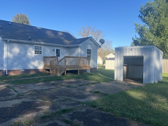 back of house with a yard, a deck, a garage, and an outdoor structure