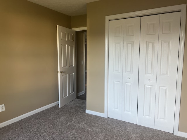 unfurnished bedroom featuring a closet and dark colored carpet