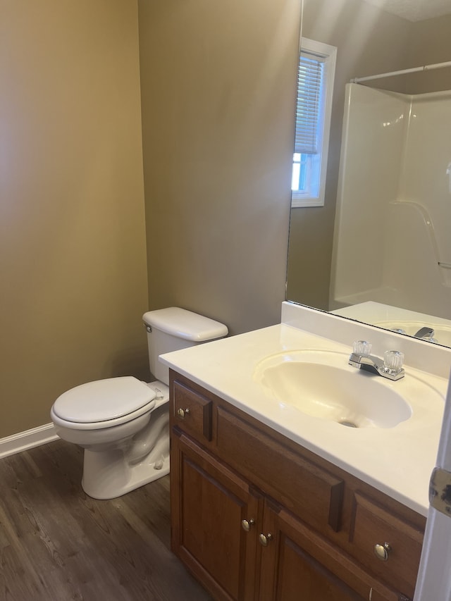 bathroom featuring hardwood / wood-style floors, vanity, toilet, and walk in shower