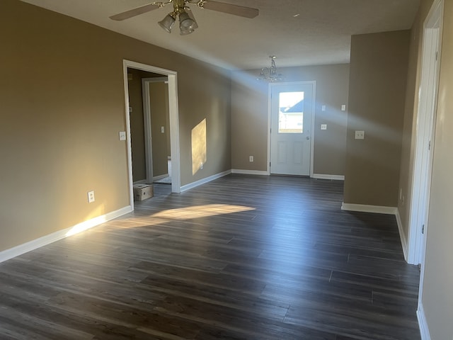 empty room featuring dark wood-type flooring and ceiling fan with notable chandelier