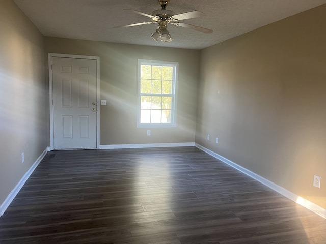 spare room with a textured ceiling, ceiling fan, and dark wood-type flooring