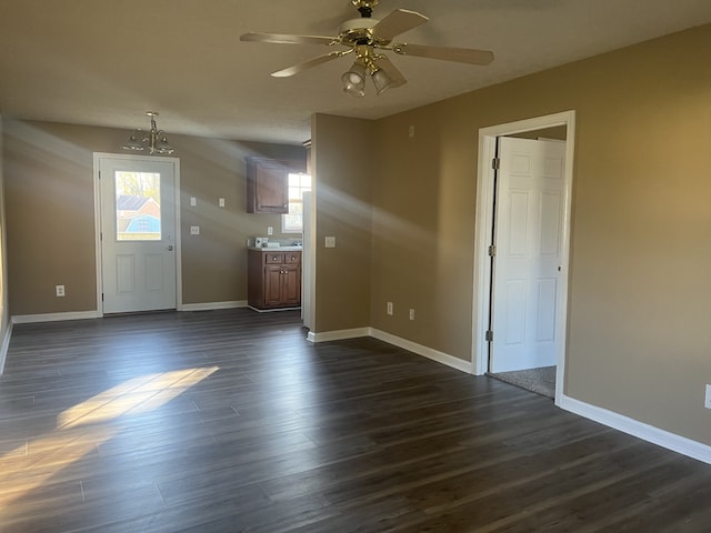 interior space with ceiling fan with notable chandelier and dark hardwood / wood-style flooring