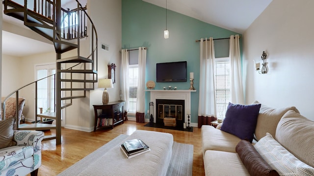 living room with high vaulted ceiling, light hardwood / wood-style flooring, and a wealth of natural light