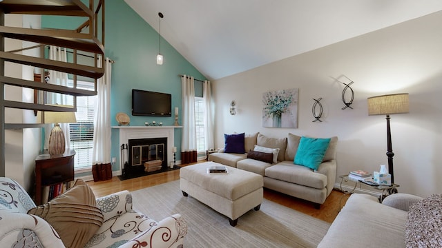 living room with light hardwood / wood-style floors, high vaulted ceiling, and a wealth of natural light