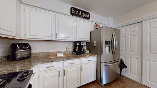 kitchen featuring stovetop, light stone counters, white cabinetry, and stainless steel refrigerator with ice dispenser